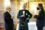 3 people at a formal drinks reception one in a kilt