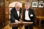 two people in black tie looking at a seating plan