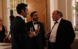 three men in black die chatting and holding drinks