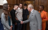 The Prince of Wales shaking hands with a student, others watch on