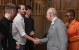 The Prince of Wales shaking hands with a student, others watch on