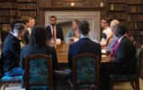 The Prince of Wales and valerie amos seated at a formal table with a large group of students