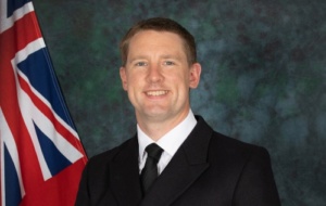 Man smiling wearing a suit with a union jack in the background