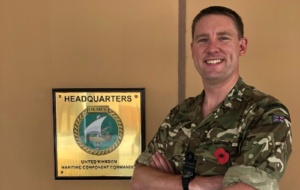 Man smiling in army uniform wearing a poppy at headquarters