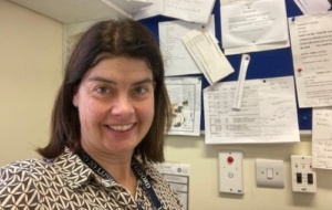 Woman smiling in front of noticeboard in her office