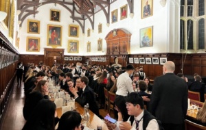 Photo of a lively formal dinner in hall, people are smiling, eating and having