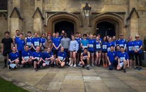 large group of runners in blue posing for picture
