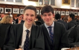 two young men smiling for the camera at a formal dinner in hall