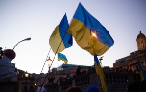 Ukraine flags held by protestors flying a clear sky