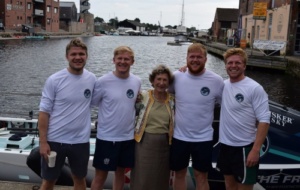 Four brothers standing with their grandmother in front a rowing boat in a harbour