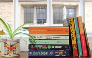 a stack of books on a window ledge with a plant