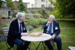 two smartly dressed elderly men seated and in conversation