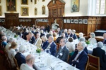 a large group pf smartly dressed people at a formal dinner in hall