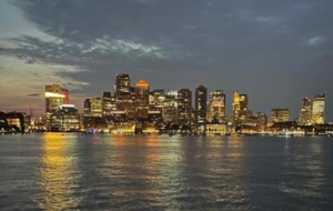 Boston skyline at night with lights reflected in water.