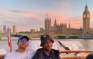 Man and friend on boat in front of Houses of Parliament