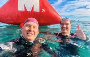 Two men wearing wetsuits in the sea smiling