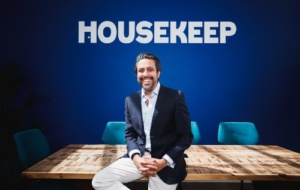 Man sitting on desk with "Housekeep" in background 