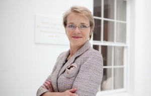 Dame Julie Maxton: woman with crossed arms smiling at camera