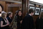 people smartly dressed entering a wood-panelled room