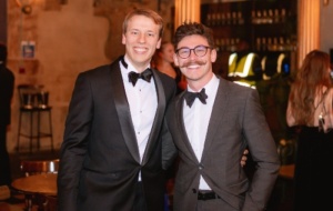 Two people in black tie smiling