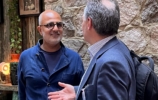 A bald man with glasses in conversation with another