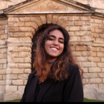 Woman with ginger wavy hair smiling in front of Radcliffe Camera