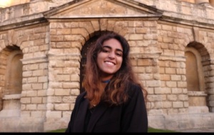 Woman with ginger wavy hair smiling in front of Radcliffe Camera