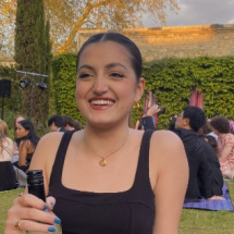 Woman smiling in Oxford garden holding a bottle of wine