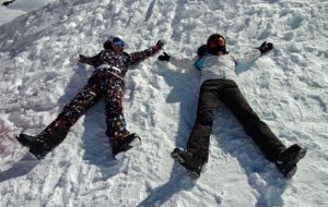 Two people in ski gear making snow angels