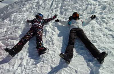 Two people in ski gear making snow angels